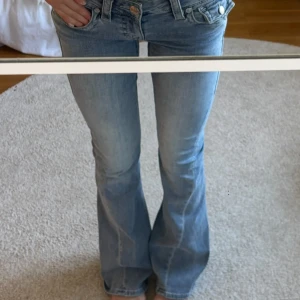 Bootcut jeans från True Religion - Snygga ljusblå bootcut jeans från True Religion med klassiska detaljer och dekorativa bakfickor. Jeansen har låg midja, utsvängda ben och är tillverkade i mjukt denim. Nästan aldrig använda, i storlek 25/32, säljer då dom är lite stora🥰