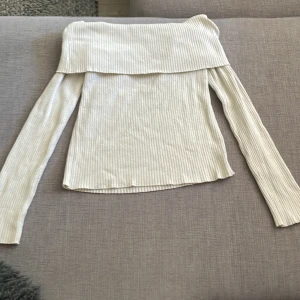 Offshoulder ribbad tröja från H&M - Superfin offshoulder tröja från H&M i ribbad, ljusbeige bomullsmix. Långärmad och croppad modell som sitter snyggt över axlarna. Perfekt till jeans eller kjol för en trendig look.