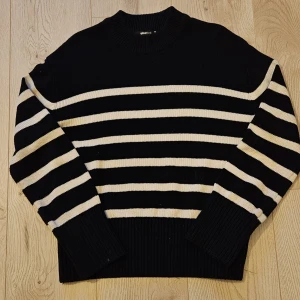 Svartvit randig stickad tröja Gina Tricot - Säljer en svart stickad tröja från Gina Tricot med vita horisontella ränder. Tröjan har rund halsringning, långa ärmar och breda ribbade muddar vid ärmslut och nederkant. Storlek XS. 
