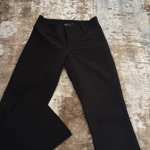 Svarta kostymbyxor från Gina Tricot XS - Svarta kostymbyxor från Gina Tricot Byxorna har två knappar och dragkedja framtill samt fickor med lock och knapp bak, de är även utsvängda ner till storlek xs