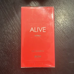 Boss Alive Intense Eau de Parfum 30ml - Boss Alive Intense från Hugo Boss är en fruktig och söt parfym med inslag av amber, trä och varma kryddor. Flaskan är rektangulär i glas med en snygg röd toning och guldfärgad kork. Perfekt för dig som gillar dofter med både fruktiga och varma, kryddiga noter. Hör av er vid minsta lilla fråga eller fundering. Helt ny och oöppnad. 