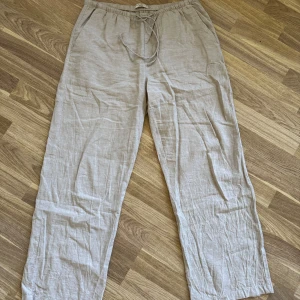 Beige linnebyxor från Gina Tricot - Beige linnebyxor från Gina Tricot med avslappnad passform och snörning i midjan. Perfekta för varma dagar, med elastisk midja och raka ben. Lätta och luftiga i materialet, passar till allt. Använda ett fåtal gånger.