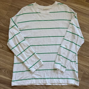 Vit randig långärmad tröja Gina Tricot - Vit långärmad tröja från Gina Tricot med gröna ränder. Enkel och clean design med rund halsringning och relaxed fit. Perfekt för dig som gillar en stilren och chill vibe. Tillverkad i mjuk bomull för skön känsla hela dagen.