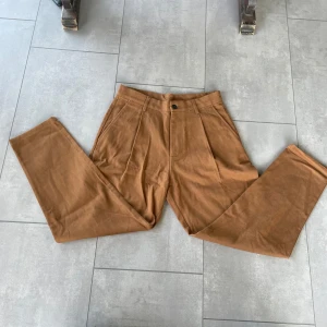 Bruna manchesterbyxor från Zara - Snygga bruna manchesterbyxor från Zara i rak modell med hög midja. Byxorna har pressveck framtill, hällor för bälte och fickor både fram och bak. Perfekta för en trendig och avslappnad look.