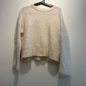 Ljusbeige stickad tröja & Other Stories - Supermjuk och fluffig ljusbeige stickad tröja från & Other Stories. Tröjan har en avslappnad passform, rund halsringning och långa ärmar. Perfekt för lager-på-lager och ger en cozy vibe till din outfit.