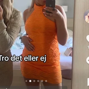Orange kort klänning från Gina Tricot - Superfin orange kort klänning från Gina Tricot med glittriga detaljer och vågigt strukturmönster. Hög hals med knäppning bak och ärmlös design. Perfekt för dig som vill sticka ut med färg och cool textur.