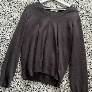 Mörkbrun kashmirtröja från Lochmere - Mysig mörkbrun kashmirtröja från Lochmere med v-ringad hals och ribbade muddar. Långärmad och i en klassisk, lite loose passform som är perfekt för lager-på-lager. Supermjuk och maskintvättbar – perfekt för dig som vill ha både stil och komfort.