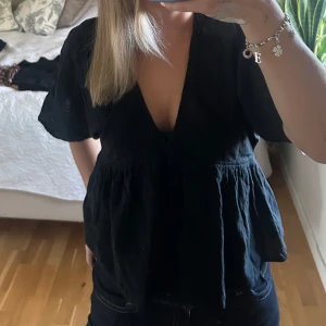 Svart blus med v-ringning från Lindex - Supersnygg svart blus från Lindex i storlek XS. Modellen har djup v-ringning, korta ärmar och en luftig, lätt rynkad passform nedtill. Perfekt till jeans eller kjol när du vill ha en enkel men trendig look.