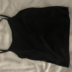 Svart enkel linnetopp - Säljer en svart, stilren linnetopp med tunna axelband. Toppen har en rak passform och är perfekt för att matcha med jeans eller kjol. Enkel och clean look som funkar till många olika stilar.