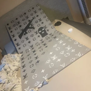 Jag säljer mina Louis Vuitton tavlor för jag flyttar ut. 1 för 700 2 för 1200 - Stort handmålat konstverk på duk med grå bakgrund, Louis Vuitton-inspirerade mönster, samt motiv av en AK47 och rånarluva. Perfekt för dig som gillar street art och vill ha något unikt och edgy på väggen.