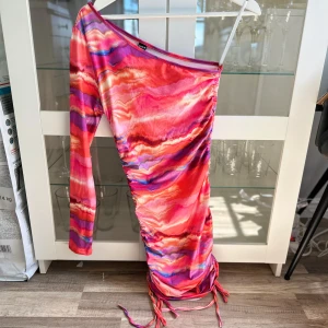 Mönstrad one-shoulder klänning med scrunch detalj - En ny oanvänd jättefin mönstrad one-shoulder miniklänning med scrunch/knyt detalj på sidan i storlek S från SHEIN ICON. Säljs pga att den blivit för liten. FÖRST TILL KVARN!