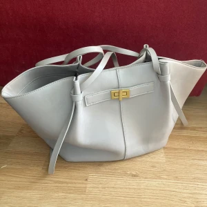 Long strap pu bag - Beige med guld spänne - Stor väska från Gina Tricot. Material liknar läder, dubbla långa handtag, spänne i guld och innerfack. Passar perfekt för skola/jobb/resa då den är rymlig och snygg. 💕