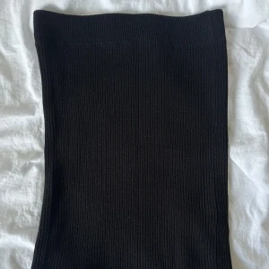 Svart ribbad kortkjol - Säljer en svart, tight ribbad kjol med stretchig passform. Kjolen är kort och sitter högt i midjan, perfekt att styla med crop tops eller oversized tröjor. Enkel och stilren design utan detaljer, passar dig som gillar minimalistiskt mode