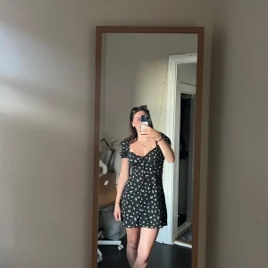 Blommig kortklänning från H&M Divided - Supersöt svart kortklänning från H&M Divided med små blommor i vitt och rosa. 