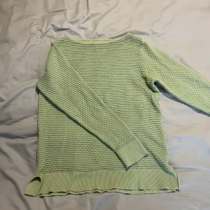 Ljusgrön stickad tröja från Stockh LM - Säljer en ljusgrön stickad tröja från Stockh LM i storlek M. Tröjan har ett vågigt strukturerat mönster, ribbade muddar och nederkant samt lång ärm. Perfekt för dig som gillar en chill och stilren look.