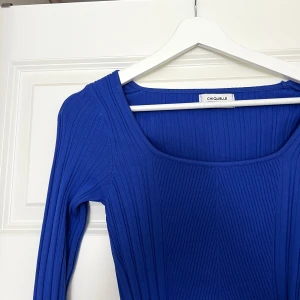 Blå ribbad topp  - Säljer en snygg blå ribbad topp från Chiquelle med lång ärm och croppad passform. Toppen har en fyrkantig ringning och är tillverkad i stretchigt material som sitter skönt på kroppen. 