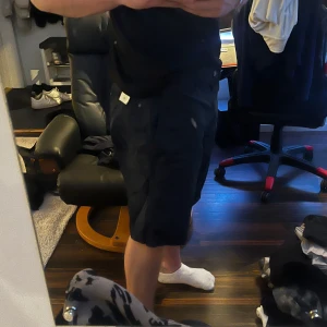 Mörkblåa chinosshorts herr - Säljer ett par mörkblåa chinosshorts med normal passform. Shortsen har knäppning fram, sidofickor och två bakfickor med knapp. Perfekta för sommaren och har en stilren look som passar till mycket. Små o storleken, jag har 34/36 i midjan och jag kan ha dessa utan problem.