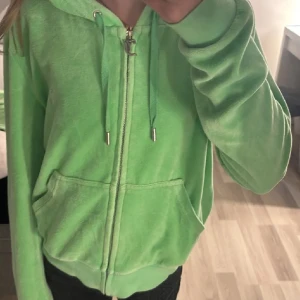 Grönt set från Juicy Couture - Säljer en ljusgrönt velour set från Juicy Couture med dragkedja, huva och fickor framtill.  . Perfekt för en avslappnad och trendig look.