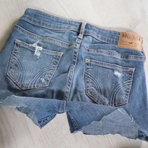 Low waist shorts från Hollister - Snygga jeansshorts från Hollister i en klassisk blå denimfärg. De har en fransig kant och slitna detaljer för en avslappnad look. Perfekta för sommardagar! Priset kan diskuteras.🩵