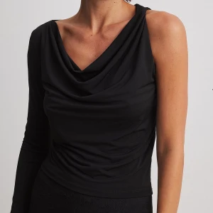Svart oneshoulder topp från NA-KD - Säljer en svart långärmad topp från NA-KD med draperad halsringning och oneshoulder-design. Snygg och trendig modell som passar perfekt till många olika outfits.