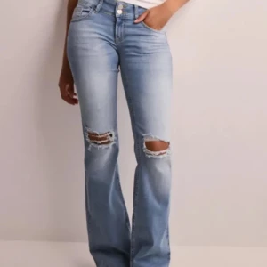 Ljusblå bootcut jeans med hål på knäna - Säljer ett par ljusblå bootcut jeans från Nelly, säljer för att jag använder typ aldrig .