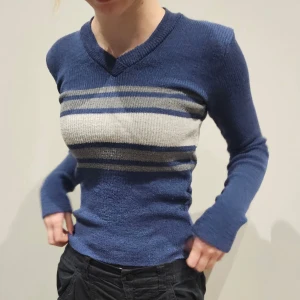 Blå stickad tröja med ränder - Tröjan är figursydd; perfekt till jeans eller kjol. Den verkliga färgen är något "kallare" än på bild.