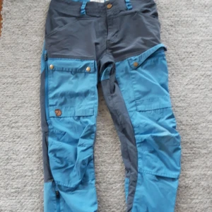 Keb pants vandringsbyxor Fjällräven - Säljer ett par friluftsbyxor från Fjällräven, modell Keb W, längd Regular. Byxorna har förstärkta partier och är perfekta för vandring. Justerbara benslut. Använt skick, se bilder på defekter, lite trasiga i grenen samt lite slitet i tyget baktill. Nypris ca 1600- 2000 kr.