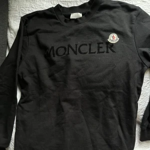 Svart långärmad tröja från Moncler - Säljer en svart långärmad tröja från Moncler med broderad logotyp på bröstet och Moncler-text framtill. 