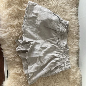 Beige linneshorts från Lindex - Säljer ett par ljusbeige shorts från Lindex i linne med elastisk midja och knytband. De har en avslappnad passform och är perfekta för varma dagar. Supersköna och luftiga med enkel design.