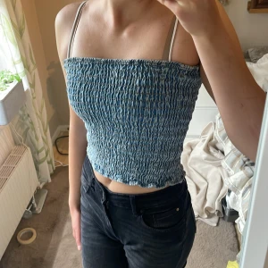 Blå smockad tubtopp  - Säljer en blå smockad tubtopp. Toppen är croppad och har en elastisk, rynkad struktur som sitter tight mot kroppen av jeanstyg. Perfekt till sommaren och enkel att matcha med jeans eller kjol. Storlek S, pris kan diskuteras🫶🏻