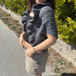 Grå stickad bolerotopp - Säljer en grå stickad bolerotopp med korta ärmar och snygg kabelstickad struktur. Perfekt att slänga över en topp för en cool lager-på-lager-look. Snygg och trendig detalj till din outfit!