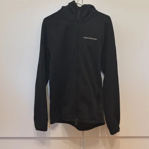Svart fleece ziphoodie från Peak Performance - Svart fleecejacka från Peak Performance med huva och dragkedja framtill. Inga täcken på användning. Vid snabb affär kan priset diskuteras. 