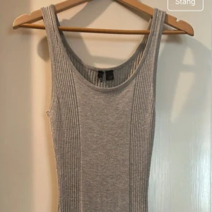 Grå ribbad ärmlös klänning - Säljer en grå ribbad klänning med ärmlös design och rund halsringning. Klänningen är figurnära och är stretchigt i materialet passar XS/S möjligtvis M.