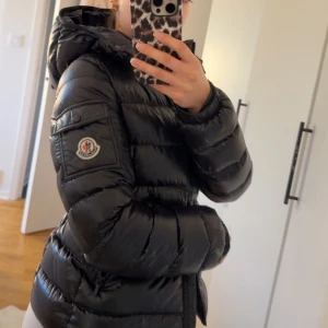 Svart dunjacka från Moncler - Säljer en svart, glansig dunjacka från Moncler. Perfekt både till vår, höst och vinter och riktigt snygg passform. Jackan är köpt på Farfetch för ungefär 2 år sedan men den är sparsamt använd. Den är i barnstorlek ”12 yrs” och skulle kunna motsvara xxs. Extra knappar följer med.