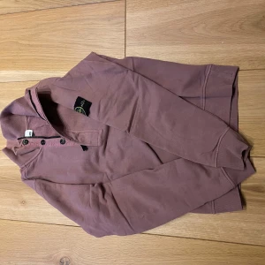 Tröja med krage - Säljer en tröja från Stone Island med knappar vid halsen. Tröjan har långa ärmar och är tillverkad i mjuk bomull, perfekt för en avslappnad stil.