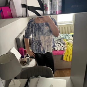 Blå och vit blus med batikmönster - Säljer en luftig blus i blått och vitt med batikmönster. Blusen har trekvartsärm och en lös passform med resår vid halsringningen. Perfekt för vår och sommar!