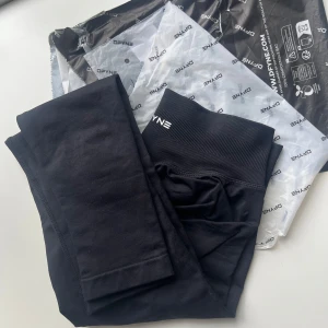 Svarta tights impact från DFYNE - Säljer ett par svarta tights från DFYNE med hög midja och bred resår. Perfekta för träning och har en stilren design med logga på linningen. Materialet är stretchigt och följsamt för bästa komfort. HELT NYA OCH ÄKTA!! 🥰