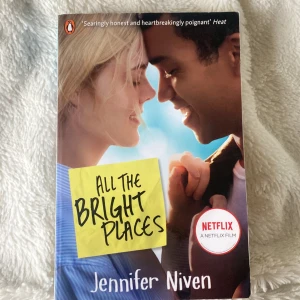 All the Bright Places - En engelskspråkig pocketbok med titeln 'All the Bright Places' av Jennifer Niven. Omslaget visar två personer som tittar på varandra mot en blå himmel. Boken är filmatiserad av Netflix och har färgglada post-it-lappar med citat på baksidan.