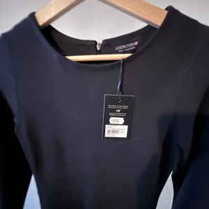 Svart långärmad klänning från Lexington - Säljer en stilren svart klänning från Lexington med lång ärm och rund halsringning. Klänningen har en klassisk, figurnära passform och dragkedja i ryggen. Perfekt för dig som gillar enkel och tidlös design.