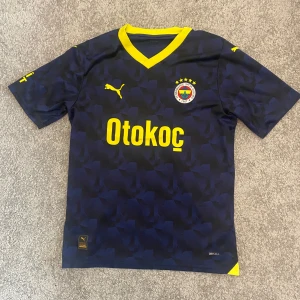 Fenerbahçe matchtröja 2023/24 tredje ställ - Mörkblå Fenerbahçe fotbollströja från Puma med gula detaljer och tryck. 