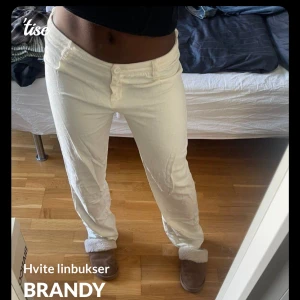 Vita linnebyxor från Brandy - Säljer ett par vita linnebyxor från Brandy med normal passform och raka ben. Byxorna har knäppning framtill och är perfekta för en avslappnad stil. Sköna och luftiga, passar bra till varmare dagar.