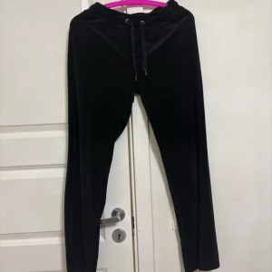 Svarta mjukisbyxor från Gina Tricot - Svarta mjukisbyxor från Gina Tricot med dragsko i midjan. Byxorna har en klassisk passform och är perfekta för en avslappnad stil. Mjukt material och elastisk midja för extra komfort.