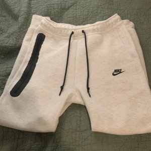 Vita byxor från Nike med snörning - Nike byxor i vitt med svart snörning och logga på vänster ben. Mjukt material och bekväm passform, perfekt för träning eller chill. Använd några få gånger. Bara att höra av sig om det är några frågor!