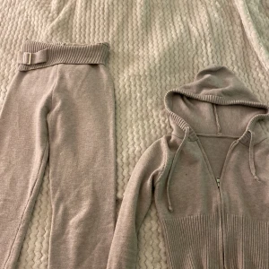 Beige stickade mjukisbyxor med bälte - Säljer ett par beige stickade mjukisbyxor med bred ribbad midja och matchande bälte. Byxorna har en mjuk och skön känsla, perfekta för en avslappnad stil. Passar dig som gillar bekväma och trendiga plagg.