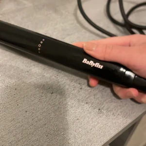 BaByliss plattång i svart och roséguld - Snygg plattång från BaByliss i svart med roséguldfärgade plattor. Perfekt för att styla håret rakt eller skapa mjuka vågor. Ergonomisk design med sladd som roterar för smidig användning. Plattorna är släta och ger ett glansigt resultat. Plattången luktar lite bränt, måste vara för att jag råkat ha plattången på för hög värme och att plattorna blivit för varma därav lukten, men funkar bra! Köpt för 800-1200kr och säljer för 110kr, pris går att diskutera! tveka inte till att lägga ett prisförslag❤️