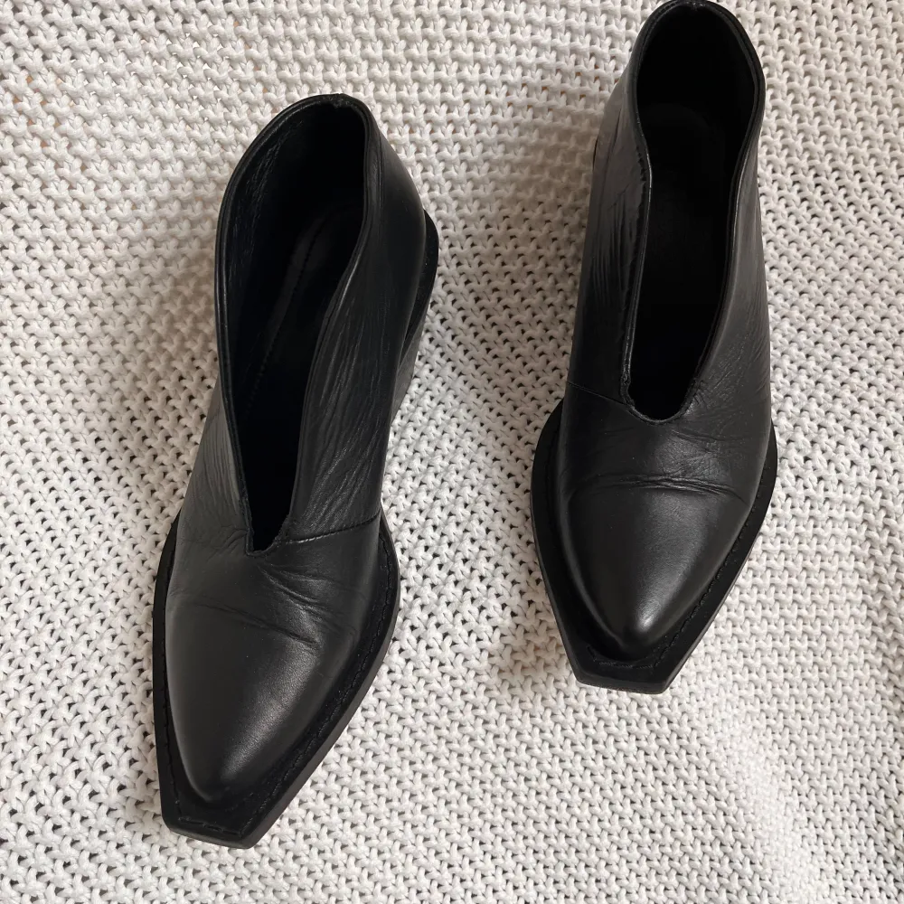 Säljer ett par svarta boots i skinn med markerad klack och spetsig tå. Öppen framtill på foten. Skorna har en cool design och ett magiskt mjukt skinn.. Kengät.
