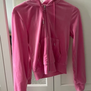 Rosa velour hoodie med dragkedja - Säljer en rosa hoodie i mjuk velour med dragkedja framtill och huva. Tröjan har långa ärmar, fickor på magen och ribbade muddar. Perfekt för en avslappnad och trendig look.❤️🥰 Hoddien är knappt använd😍