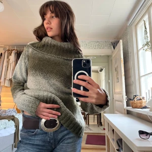 Olivgrön stickad polotröja - Super mysig olivgrön stickad polotröja med bred krage. Stickad i melerat garn och har flätat mönster på ryggen. En varm och mjuk tröja i mycket bra skick!🌿