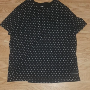 Svart t-shirt med CK-mönster från Calvin Klein Jeans - Svart t-shirt från Calvin Klein Jeans med små vita CK-loggor över hela tröjan. Klassisk rund halsringning och korta ärmar. Brorsan köpte xxl istället för xs så jag aäljer den