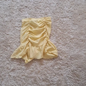 Gul volangkjol från Gina Tricot - Supersöt gul kjol från Gina Tricot i storlek XS. Kjolen har volangdetaljer och rynkade partier framtill som ger en snygg och trendig look. 